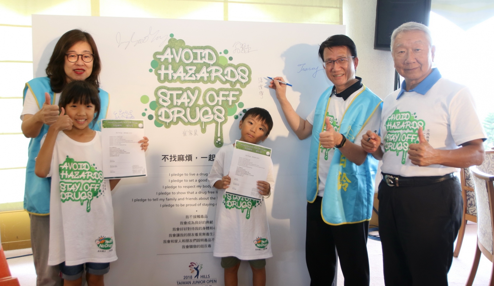 台北百齡扶輪社長杜佳莉(左一)、東華球場總經理張歐誠(右一)與中和興南國小師生一起在反毒宣誓背板上簽名。
