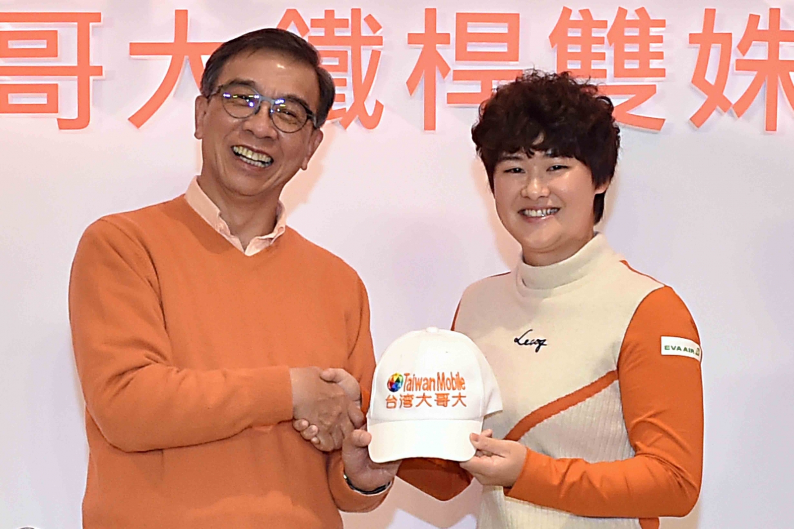 台灣大哥大總經理鄭俊卿(左)，為李旻戴上繡有台灣大的球帽。