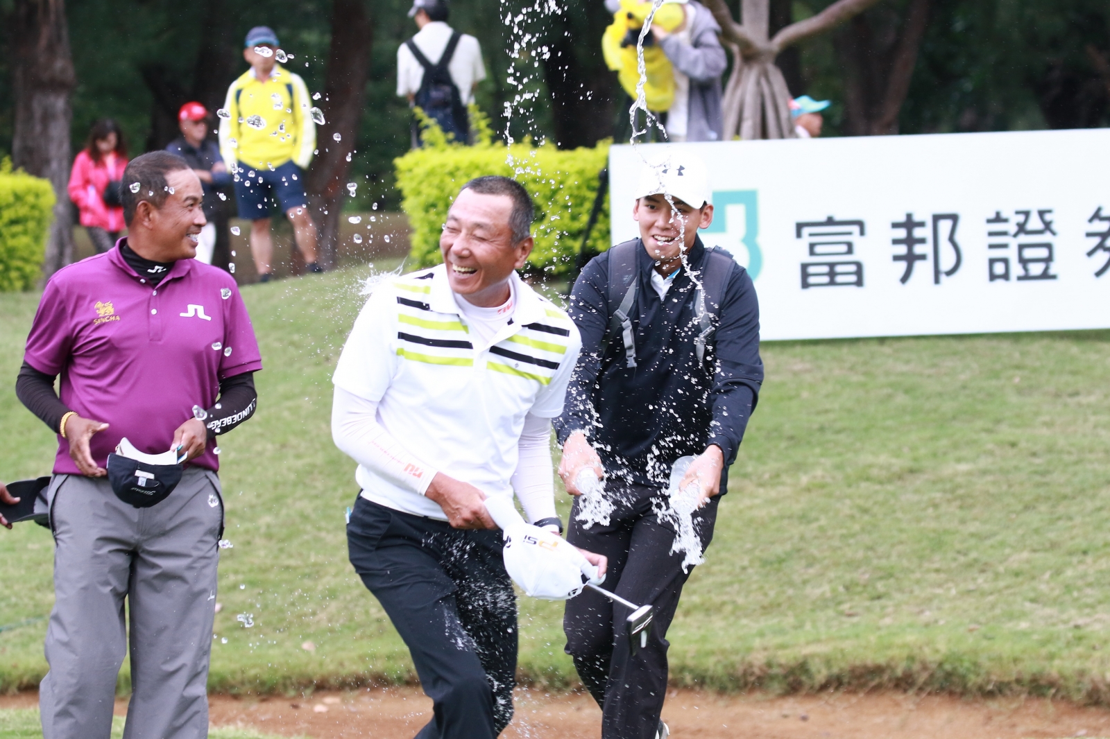 呂文德(中) 推完最後一桿確定獲勝後接受業餘球員陳威勝(右)澆水祝賀。