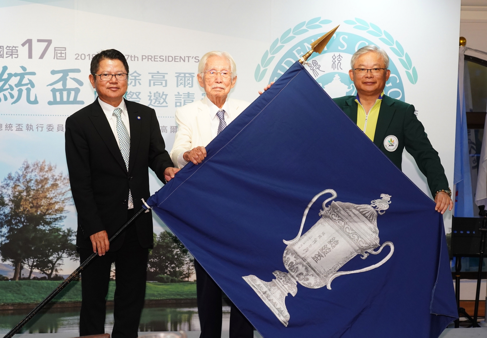左起大會會長陳茂仁將會旗歸還給創會會長辜寬敏再交給下屆主辦南一球場董事長蔡君山。