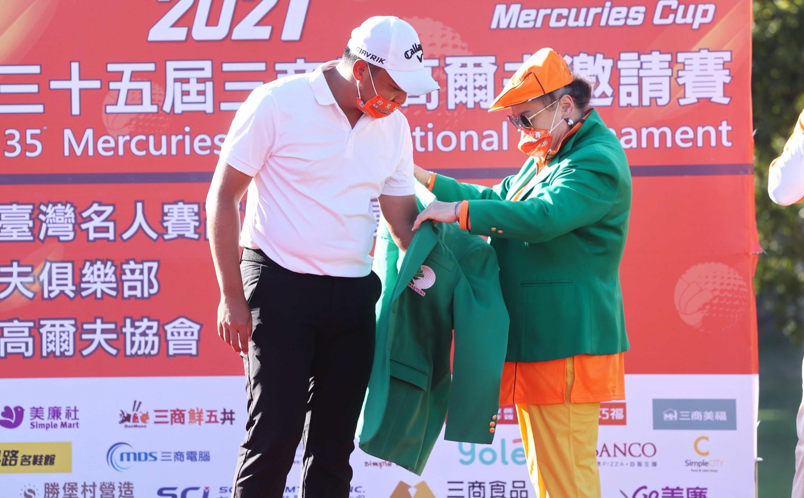 去年冠軍王偉軒人在美國拚資格賽，改由翁董事長夫人（右）為王偉祥穿上冠軍綠夾克。