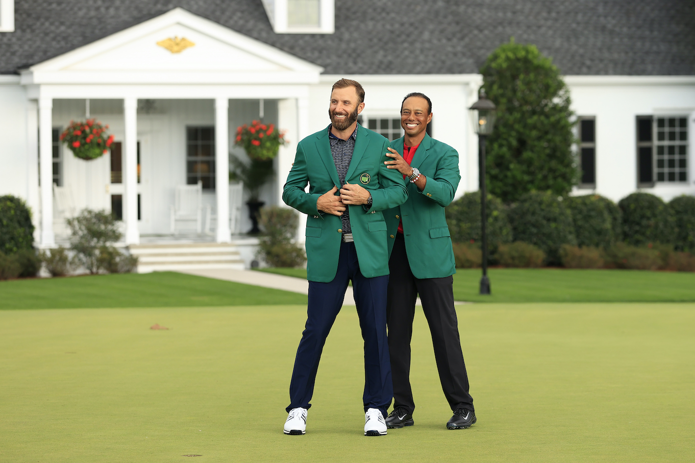 上屆冠軍Tiger Woods為本屆冠軍Dustin Johnson(前)穿上名人賽冠軍榮耀的綠夾克