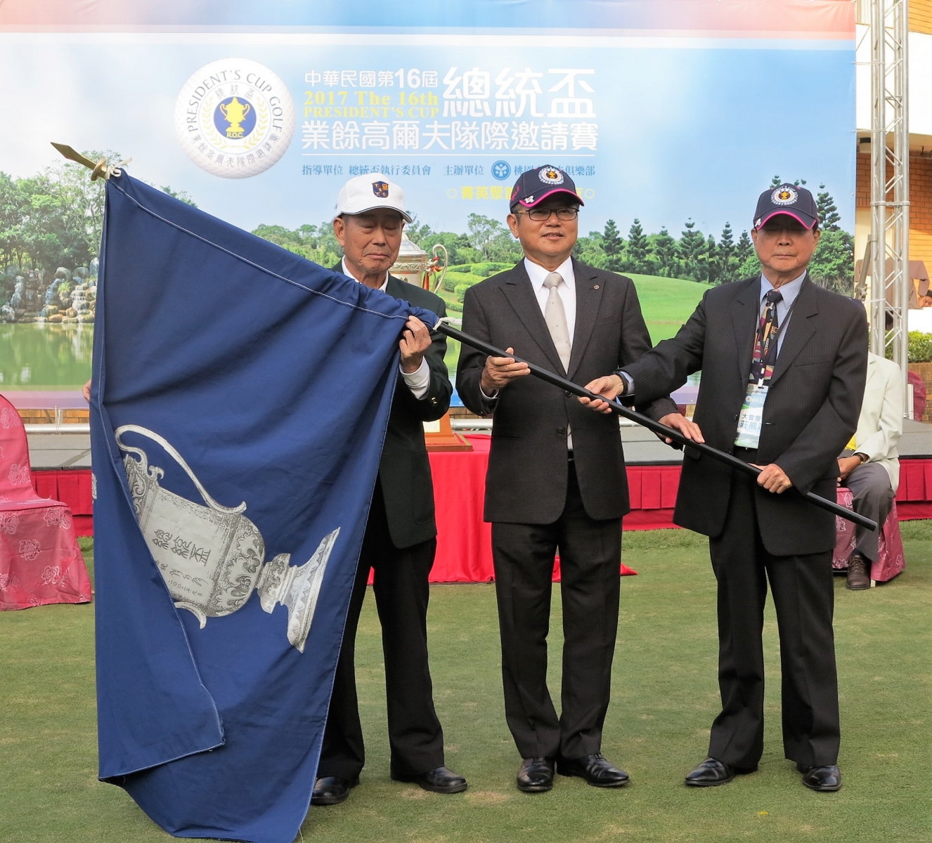 今年總統盃大會會長莊熊源(右一)將大會會旗轉交給明年承辦的台灣高爾夫俱樂部會長陳茂仁(中間)手上。