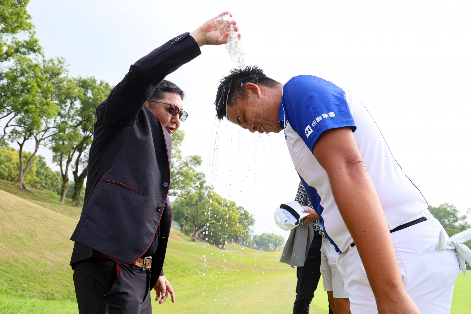 KBS TAIWAN董事長莊宇龍(左)在18洞為冠軍選手洪健堯潑水慶祝。(KBS公開賽提供)