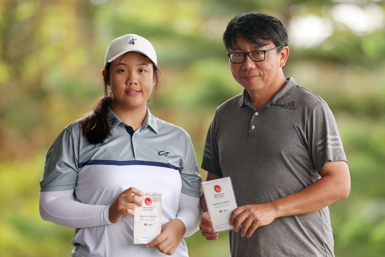 林潔恩(左) 手持黃亭瑄留給她的2022年賽事碼數本；父親林政耀(右)手上的則是大會週一晚上發下來的今年度碼數本。